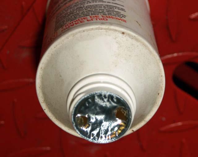 Be sure to protect your paint from drips and squirts. Open the new bottle, and puncture the foil like this.