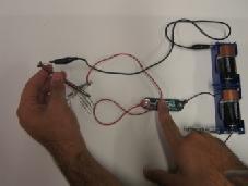 3. Have students look at the diagram on the Instruction Sheet and make the circuit by: a. Snapping the 2 wires containing snaps onto the switch. b. Clipping one of these wires to the metal bar protruding from the battery holder, using the alligator clip.