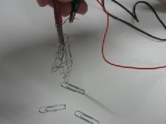 Take the 3 rd wire (with alligator clips on both ends) and clip one end onto the other metal bar on the battery holder and the remaining end of the copper wire coil. e. Ask students what they need to do to complete the circuit (press and hold the switch).