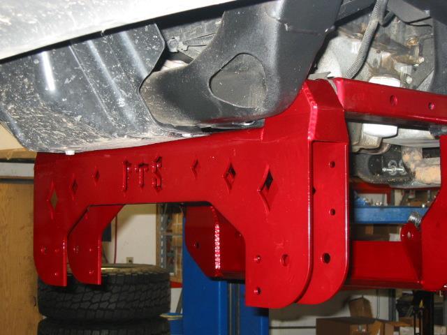 27. Next use transmission jack or two people to raise the front lower control arm drop bracket into position into front lower control arm pockets.