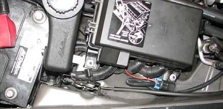 Slide intercooler reservoir brackets behind loosened fuse box nut and hood hold down latch bolt.