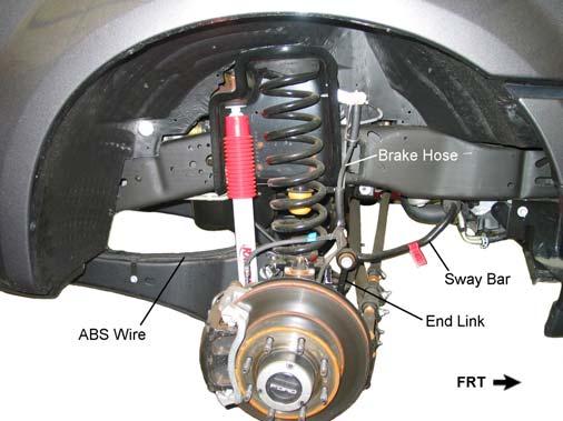 Support the front axle with two floor jacks, one under each coil spring. 2. Remove the front shock absorbers. Carefully lower the axle enough to relieve the tension on the coil springs.