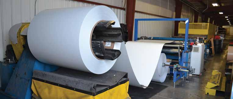 Manufacturing Painted metal coils unroll and are directed towards a form roller.