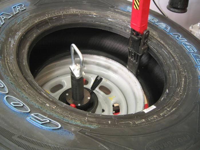 Rotate while pressing down on the tire with the upper roller. Stop when the lower bead is on the rim. Lower the lower the mount/demount head to cradle the rim.