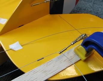 6 Make sure the control lines in the fuselage are not tangled, then attach the clips to the servo arms and mount the arms on the servos.