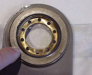 8. If bearing and thrust washers do not fall out, leave them stacked in flange (A, arrow). 9. Remove fluorocarbon seal.