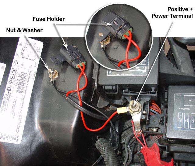 Install the fuse holder onto the negative terminal shown. Install the positive terminal of the wiring loom (Item 19) to the positive terminal shown and reinstall the stock positive terminal cover.