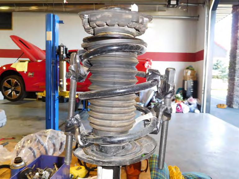 With the strut assembly supported, use spring compressors to remove tension