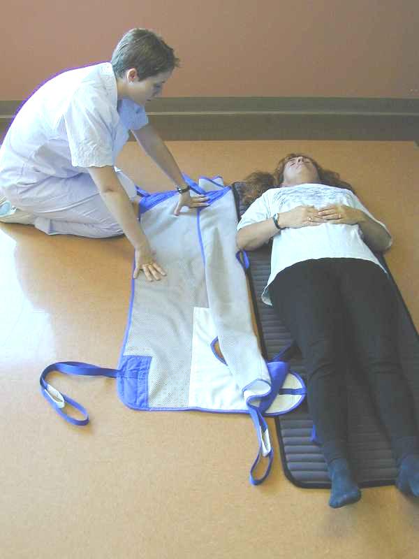 Fold the sling in half lengthwise with the white part of the sling on the inside of the fold and place next to the patient to be