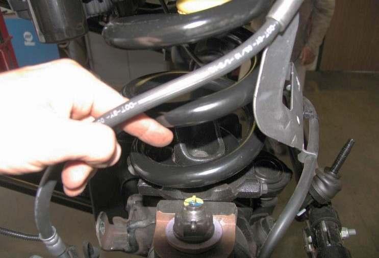 8) Disconnect the ABS sensor wire from the lower spring seat and the radius arm. 9) If equipped with auto hubs, disconnect the vacuum hose from the axle hub and frame.