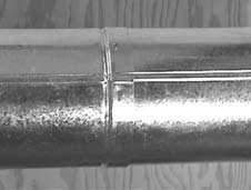 The pipe and slip section need to be secured by driving two 1/2 in. screws through the overlapping portions of the outer flues using the pilot holes (see Figure 17).