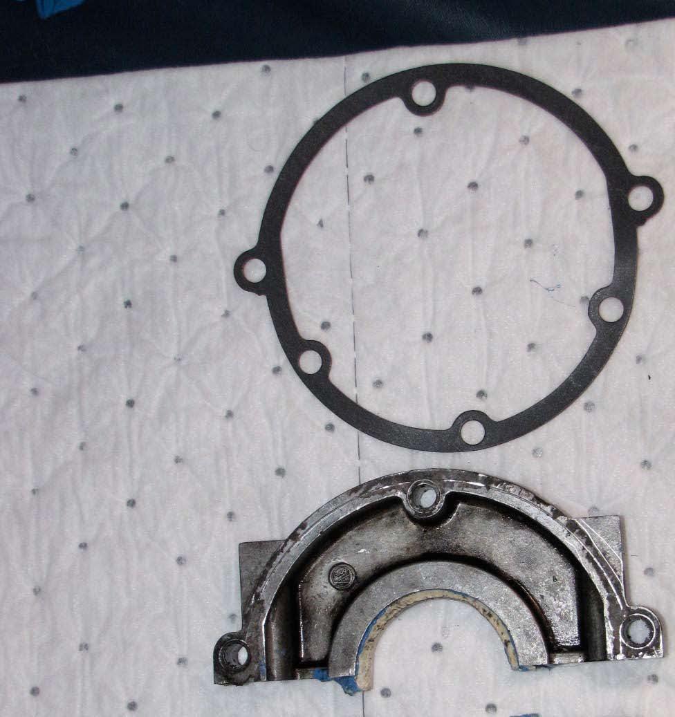 Oil seal gasket and upper half of oil seal. The oil seal gasket is positioned between the oil seal housing and the rear engine casting.