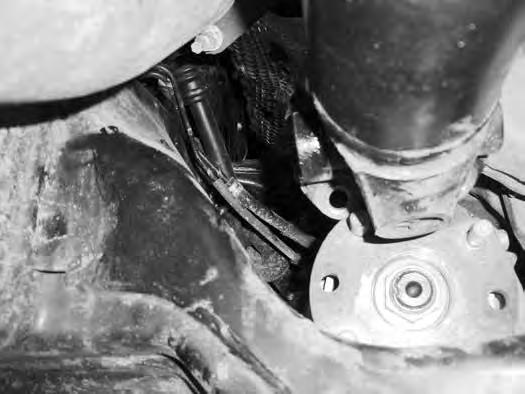 With the help of an assistant, support the front differential with a proper jack. Remove the outer bolt and inner nut mounting the rear differential bracket to the frame.