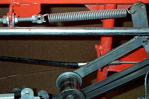 A cable runs from the clutch pedal to a support bracket. The end of the cable housing is attached to the support bracket with two nuts. The cable wire then runs to the idler roller lever.
