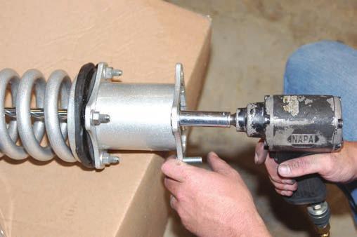 36. Disassemble the factory strut assembly with a strut compressor using a 17mm wrench and remove the strut cylinder as shown in Photo 31. 37.