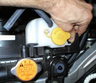 2) Then disconnect the hose from the radiator to the coolant overflow bottle, push the tab to release the