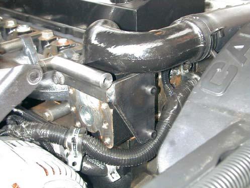 Route the hose clear of the exhaust manifold and tie it to the air conditioning line, then route it forward and down under the radiator and clear of all hot or moving parts.