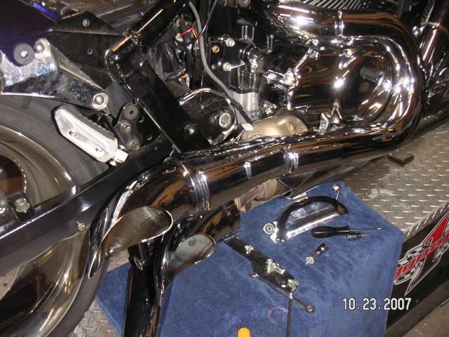 Reinstall upper tube and heat shield. Check for alignment. Tighten clamp on front of heat shield. This will hold shield and inner tube to manifold. Reinstall remaining guards, trim pieces and seat.