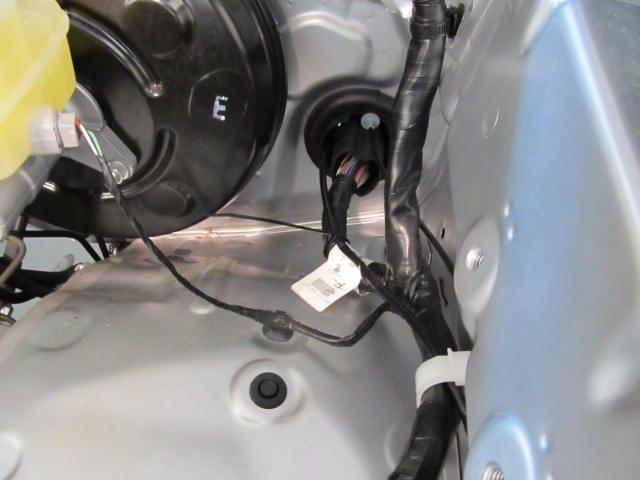 through the plastic clip 4. Locate the large vehicle harness grommet on the left side.