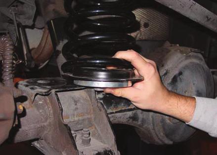 HOLD THE COIL SPRING AGAINST THE UPPER MOUNT, WHILE SLIDING LOWER SPRING PERCH INTO PLACE.