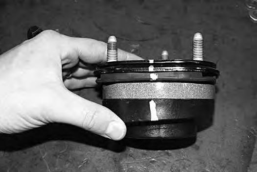 Using an appropriate strut compressor, compress the coil spring and remove the upper strut nut (Fig 14c). Remove the strut, strut cap and upper coil seat from the coil spring. FIGURE 14C 53.