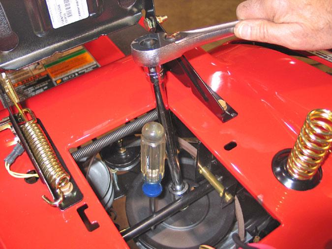 7.3. Using a spring puller or length of starter cord, remove the large spring attached between the variable speed idler arm and the rear of the tractor frame. See Figure 26. 7.5.