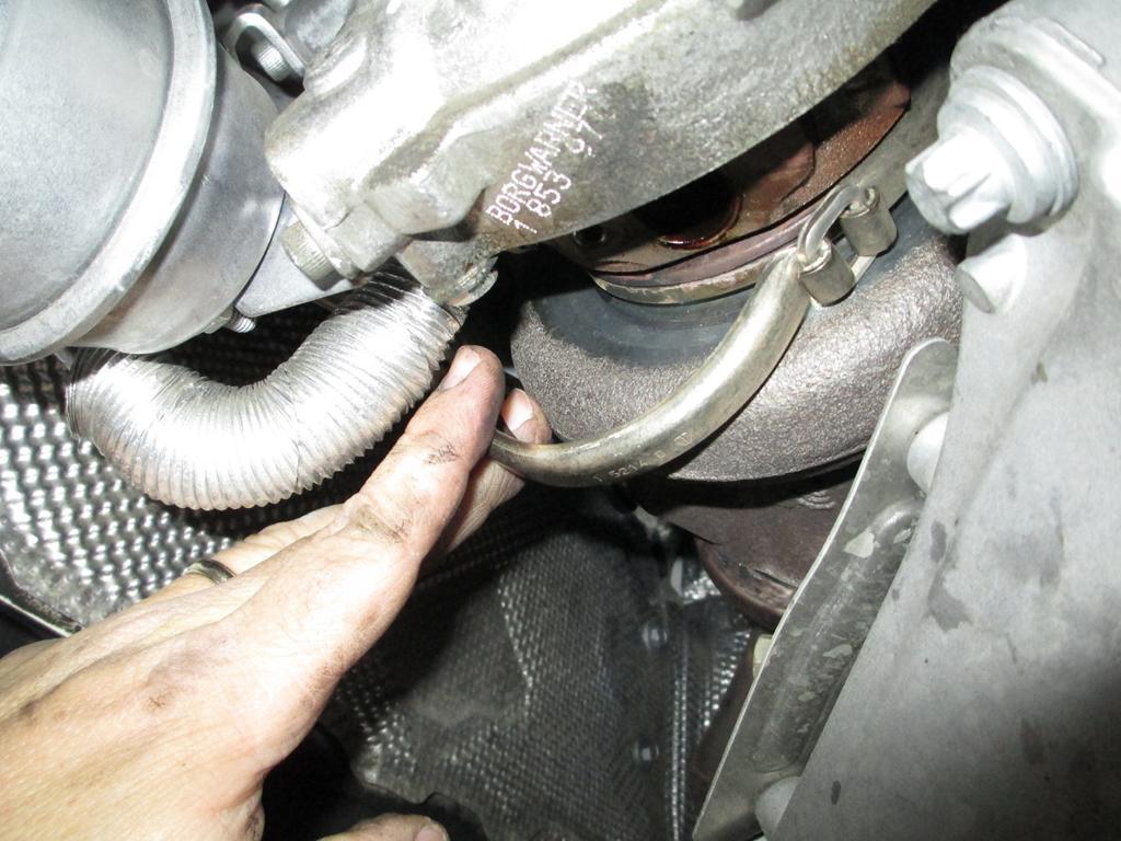 Tap the clamp with a small punch or the end of a screwdriver to break it loose from the turbo and manifold (see
