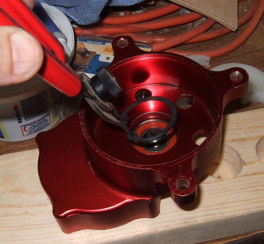 From the clutch bell side, press the pinion gear out of the bearing that supports it. This is best done with an arbor press. I did it on my drill press.