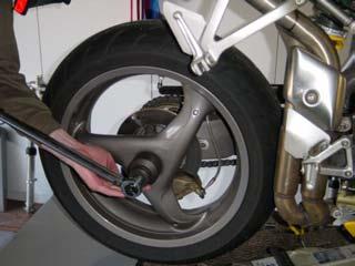 This document provides instructions for removing and installing a rear shock absorber on a Ducati Superbike with a single-sided swingarm.