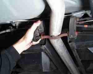 4) The next step is to remove each rear muffler from its hanger bracket. Use a 15mm socket wrench to remove the nut holding the top of the rubber insulator to the hanger bracket shaft.
