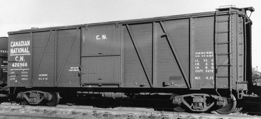 1154: Canadian National CN car with six foot door. The cars was built in 1923, and by the time of this 1957 photo had been modernized with an outside metal roof, cast steel trucks, and AB brakes.