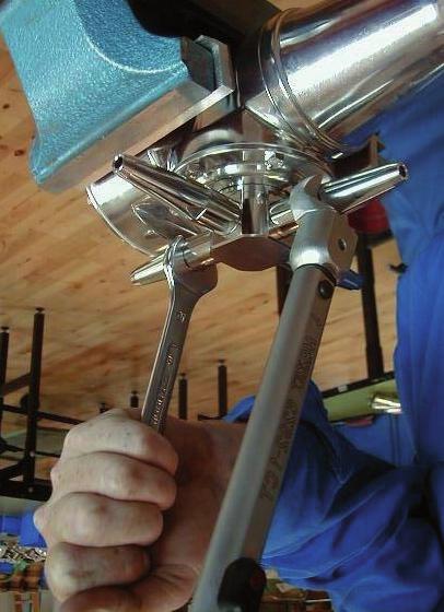 Hold one nozzle with flat spanner to counteract while tightening the opposite nozzle with the torque wrench.