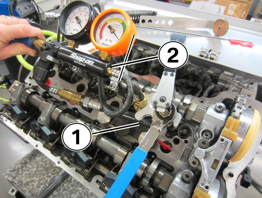 23. Remove the black plastic TDC tool from cylinder 1. Install the leak down test adaptor (1) into the cylinder spark plug hole.