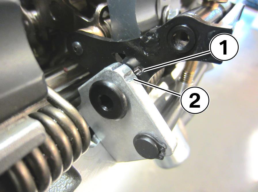 47. Continue to compress the spring until the round hole in the black arm (1) aligns with the half round machined notch in the silver aluminum frame (2). 48.
