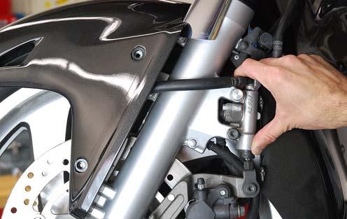 Grasp the secondary master cylinder with one hand as shown and firmly rotate the cylinder in a