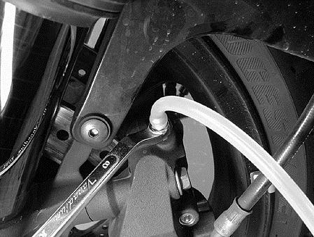 8) Remove the clear hose (). 9) Attach a clear hose () to the left side brake caliper air bleeder valve, and insert the free end of the hose into a receptacle.