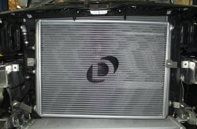 12. Install Dinan cooler into place. Slip Dinan cooler into position as shown. Examine the condition of the O-rings in the coolant lines, and replace if needed. New O-rings are included in this kit.