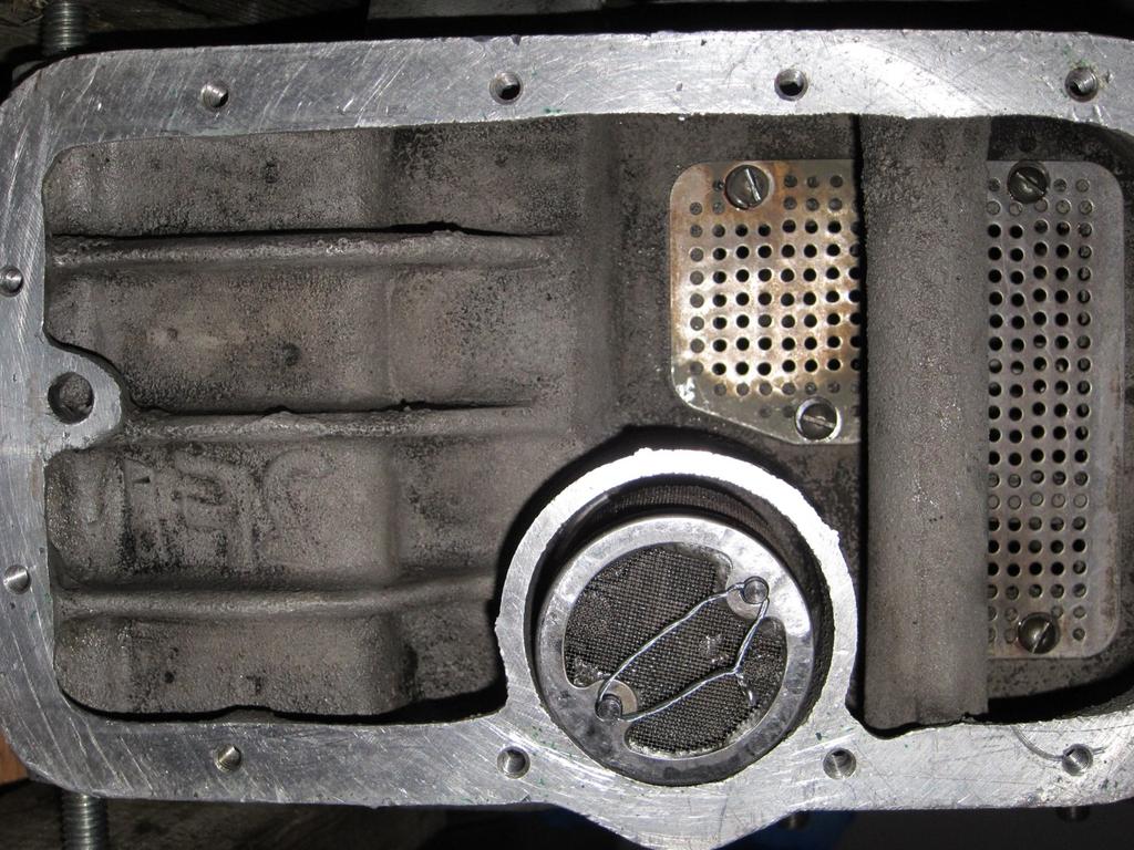 Figure 1 Oil pan cover removed showing the oil pump filter safety wired in place. Clutch Use an impact screwdriver to loosen the six bevel-headed screws.