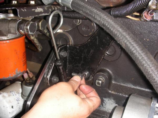 Install engine oil dipstick previously removed and align with hole which does not have fastener