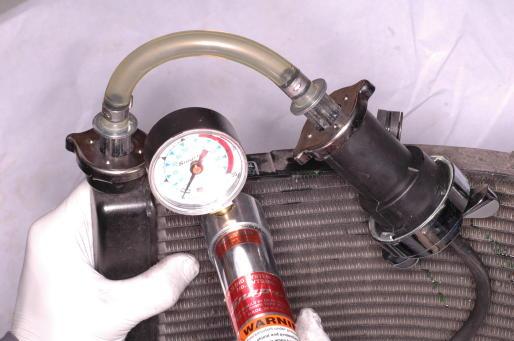 Remove the radiator cap by pushing down and turning it. Use a shop towel to hold the cap. Remove the radiator cap in two stages.