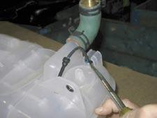 Using a standard screwdriver, loosen the hose clamps securing the hoses to the coolant surge tank and remove the hoses.