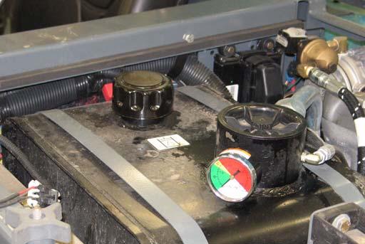 A filler cap is mounted on top of the reservoir. It has a built-in breather and fluid level dipstick. Replace the cap after every 800 hours of operation.
