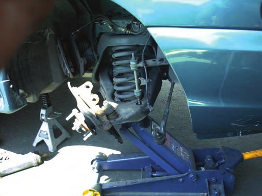 From the front of the car, place a floor jack under the control arm and slightly compress the spring to support the control arm when