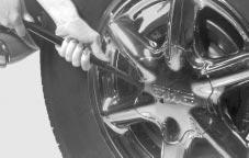 Removing the Flat Tire and Installing the Spare Tire To access the lug nuts, place the wheel wrench in the slot on