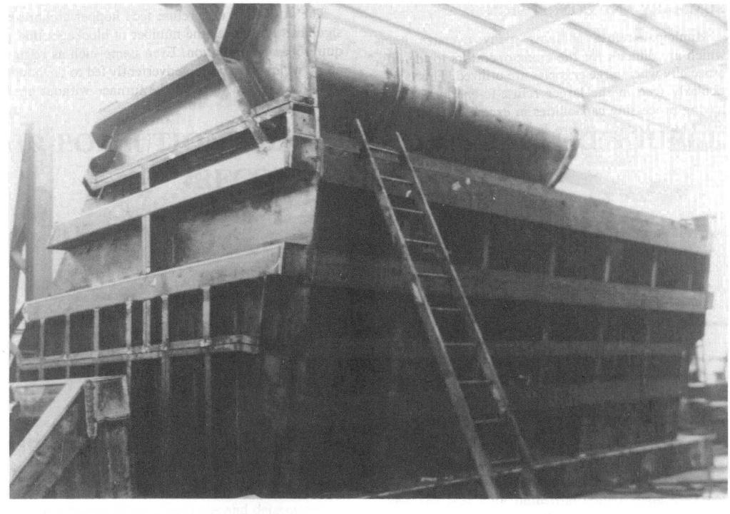 FIG.3 THE IMPROVED REFUSE FEED HOPPER WITH ARCH BREAKER ASSEMBLY IS SHOWN DURING MANUFACTURING The feed opening of the hopper is resting against the floor during assembly.
