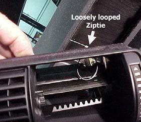 Step 13: Loosely loop the ziptie through the two holes (vent housing in picture is flipped upside down). Feed 3 of wires through the back of the housing and through the ziptie loop.
