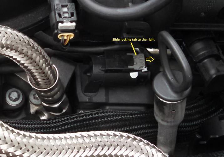 On the top of the ignition coil, slide the ignition wire socket light grey locking tab to the right to release the