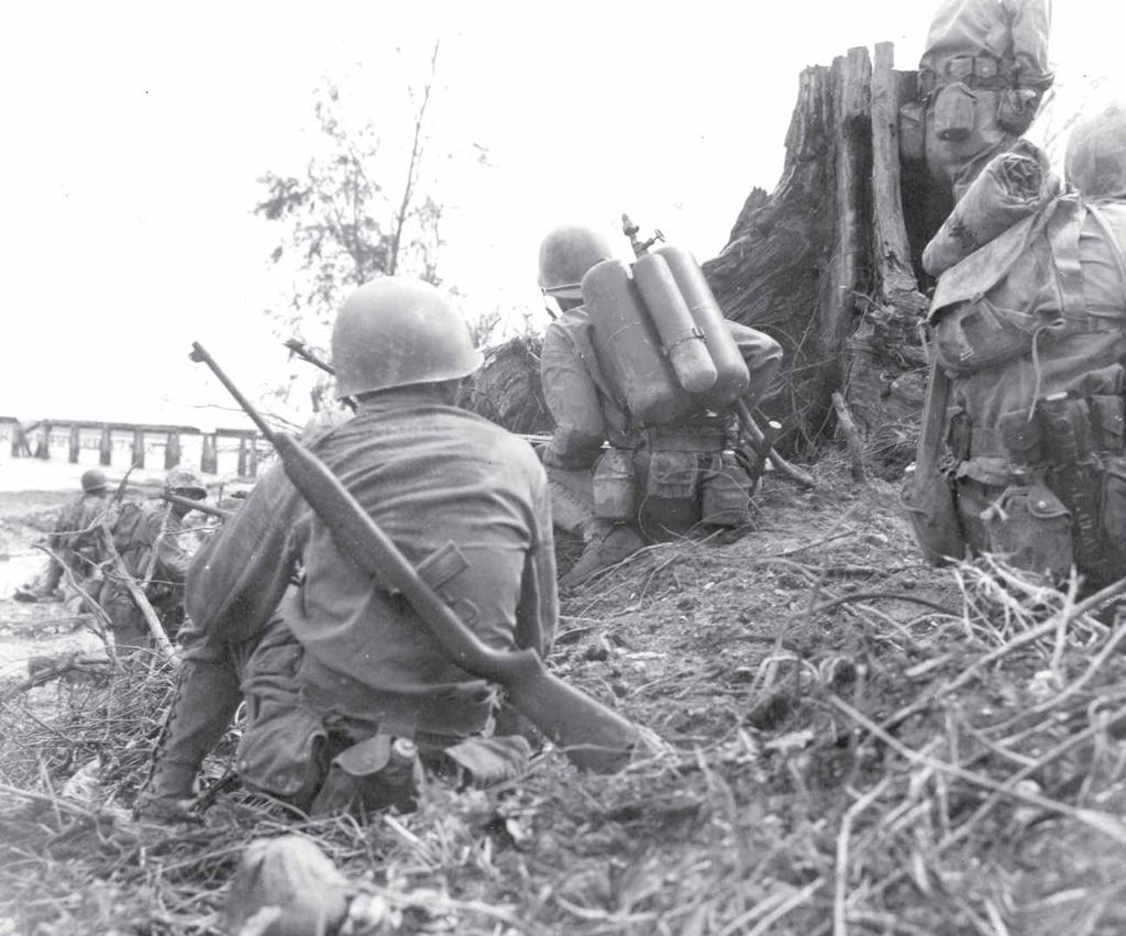 Moments after tank fire has reduced a Japanese position barring the way to the beach, infantrymen wait