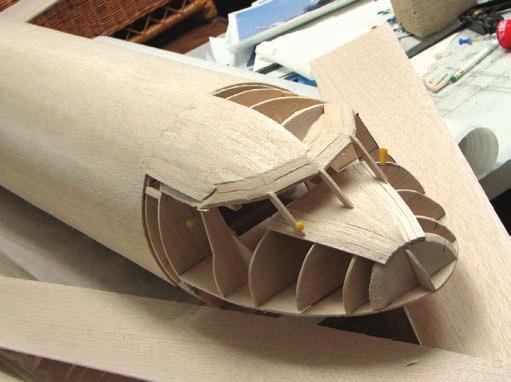 The nose section is built onto the center section while it is still pinned to the building board. Here, the upper formers have been glued into place on top of the cockpit decking piece.