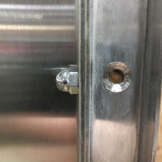6. After the two frame sections have been tightened together, fasten the frame to the wall studs using the predrilled holes within the door tracks on both sides of the door opening (see Figure 7).